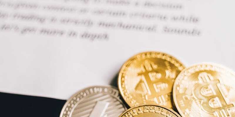 Close-up of Bitcoin and Litecoin coins on a trading strategies document.