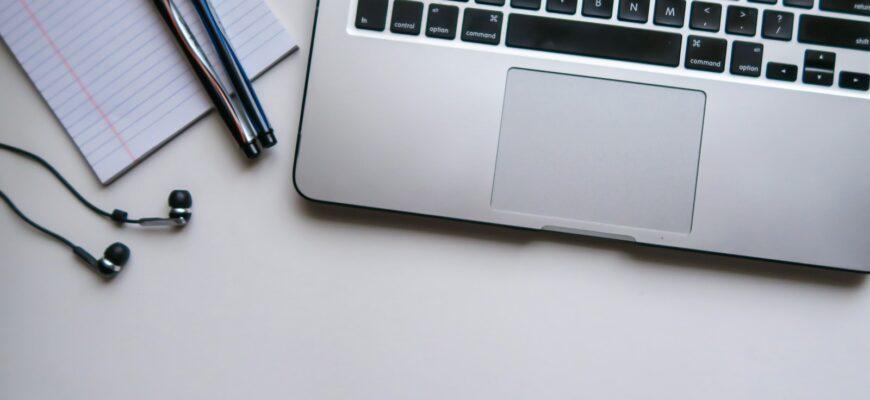 silver laptop computer beside white ruled paper